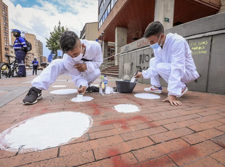 Jóvenes de 'Parceros Bogotá' pintan las franjas peatonales en los andenes. Foto Alcaldía de Bogotá