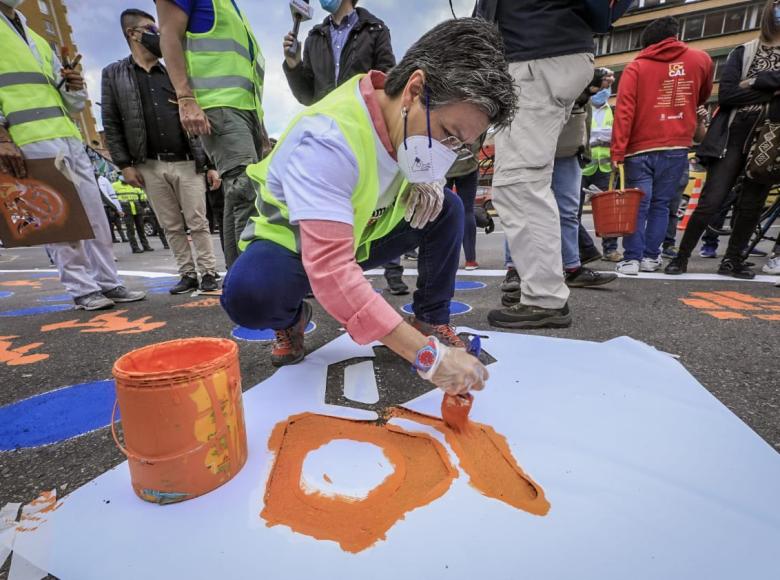 Alcaldesa Claudia López ayuda a pintar la calle con moldes decorativos. Foto Alcaldía de Bogotá