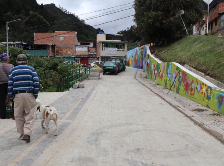 Ahora: Se construyó un nuevo muro de contención de 6 mts de alto y 28 mts de largo, al costado de la casa de Flor, además, arregló la vía, se hicieron andenes y se construyó una plazoleta con jardines. ¡Un cambio extremo!